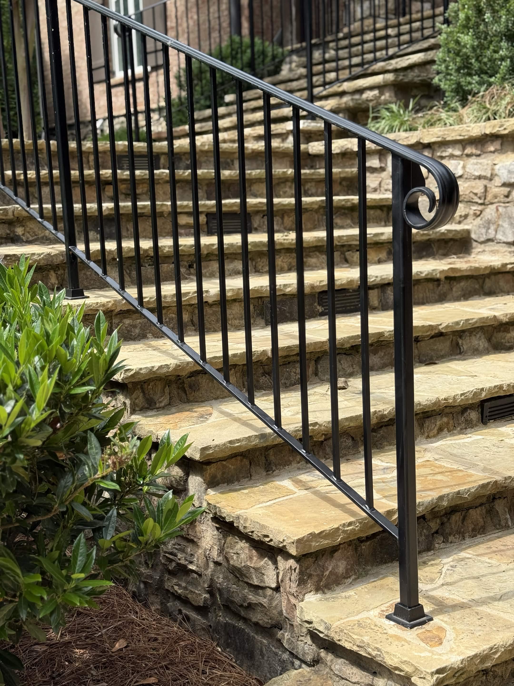 Hand-set stone steps with a custom wrought-iron handrail